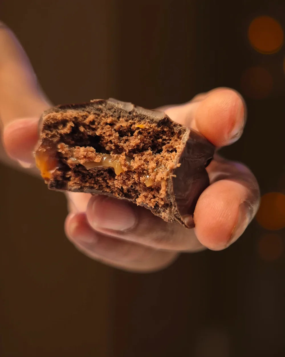 Hand holding a bitten chocolate alfajor